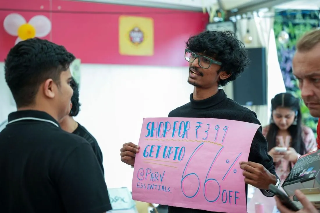 A student holding a discount sign at a market stall