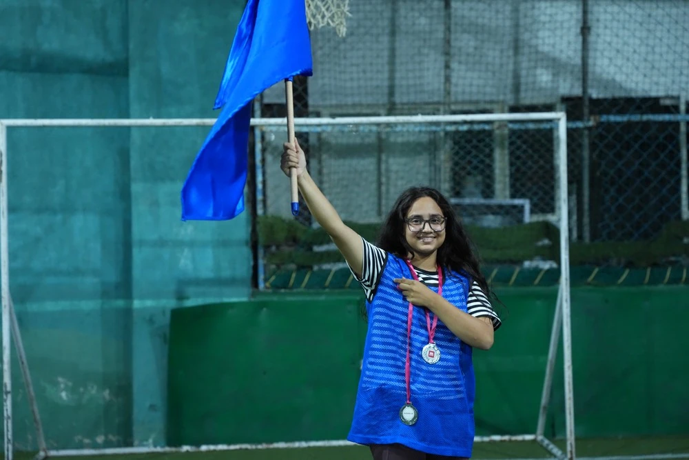 A student holding a flag with a medal round her neck