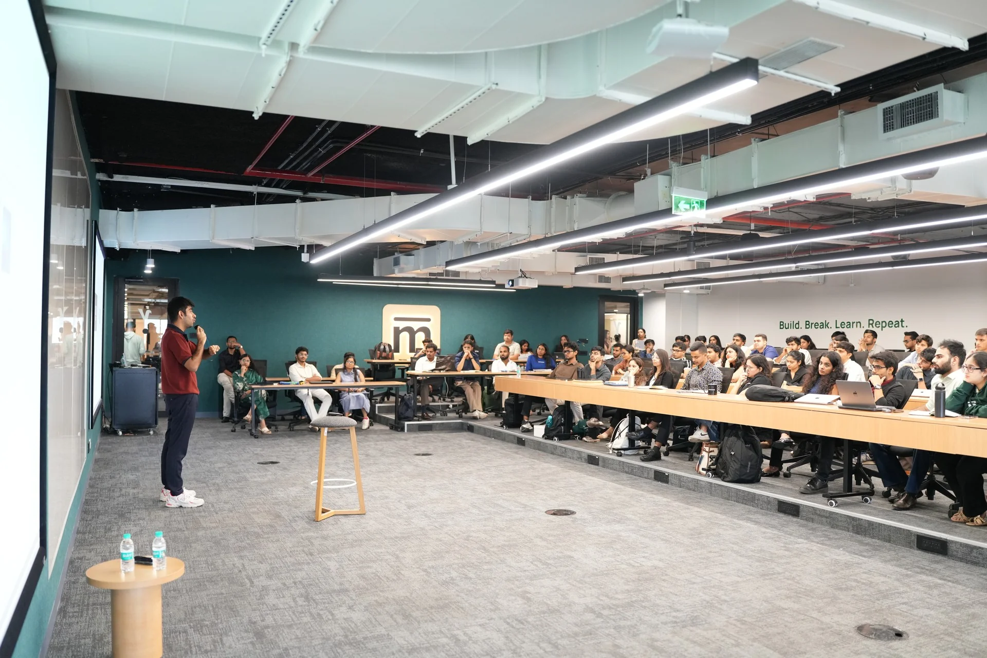 A speaker at the front of a full Mesa classroom