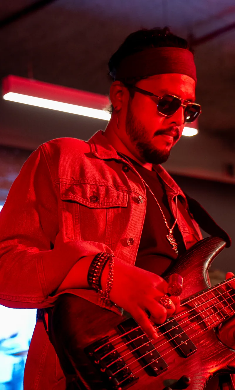 A guitarist performing under red stage lights at Maverion
